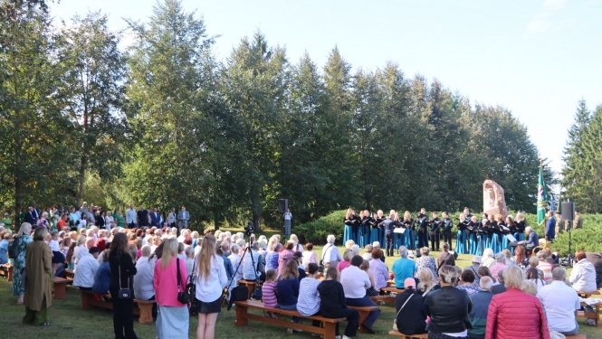 Atceres pasākuma dalībnieki klausās dziedātāju koncertu pie K.Ulmaņa pieminekļa